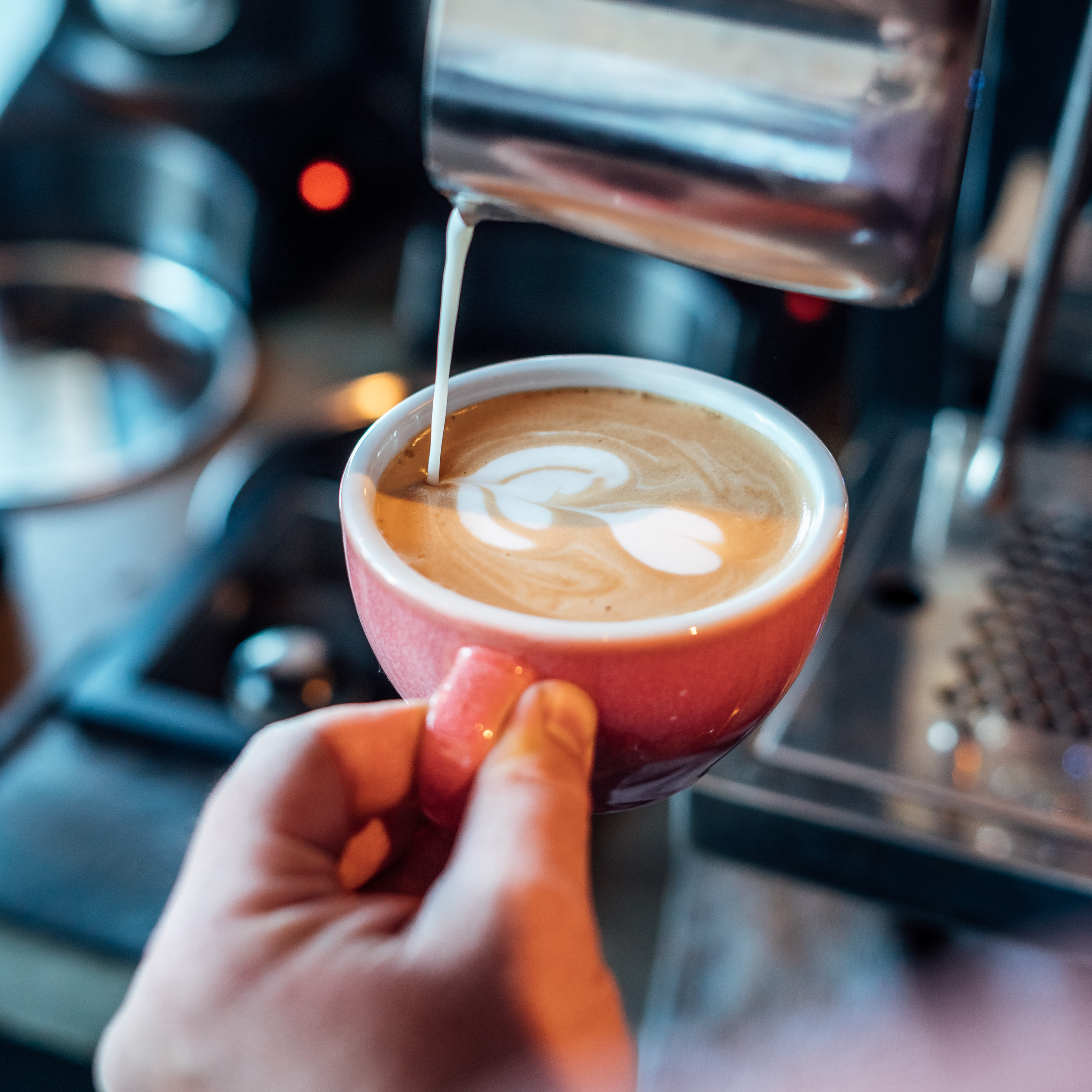 The picture depicts a latte. The motive of the latte art is a four-leafed leaf.
